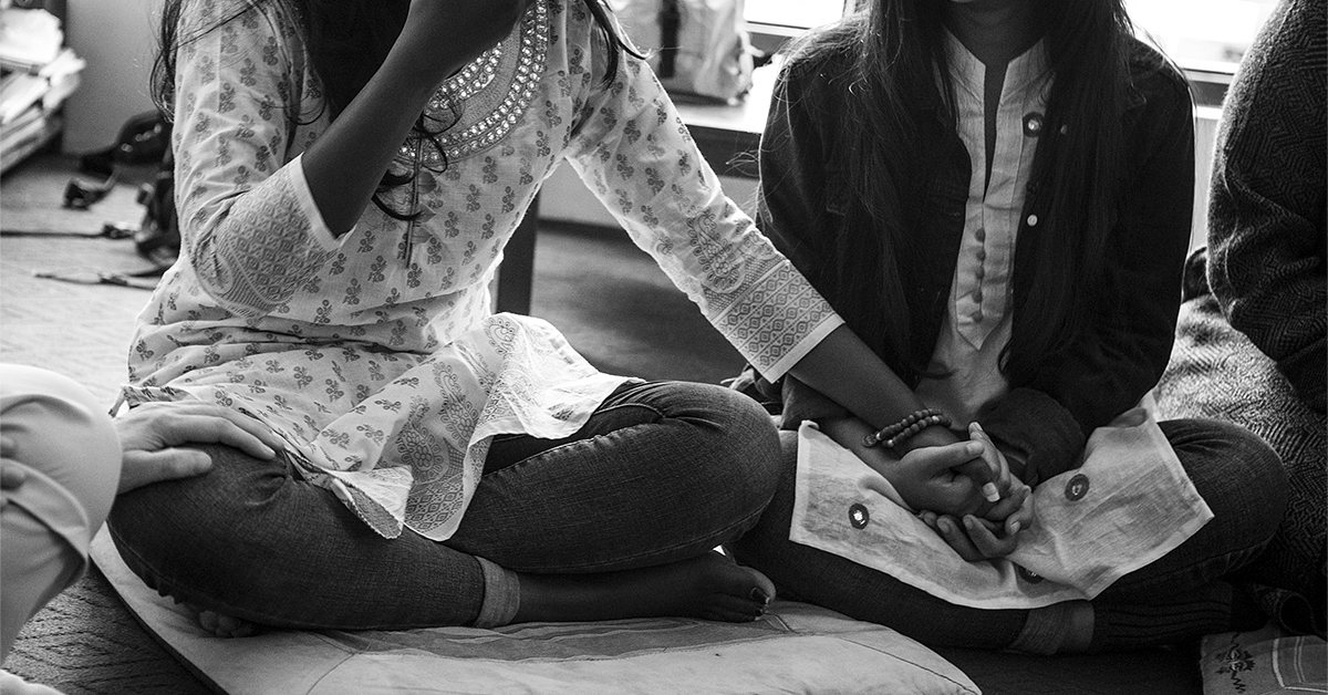 Young Nepalese women sit together and comfort a friend